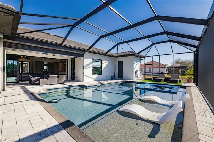 Integrated pool / hot tub featuring an outdoor hangout area, a sunroom, a patio, and glass enclosure