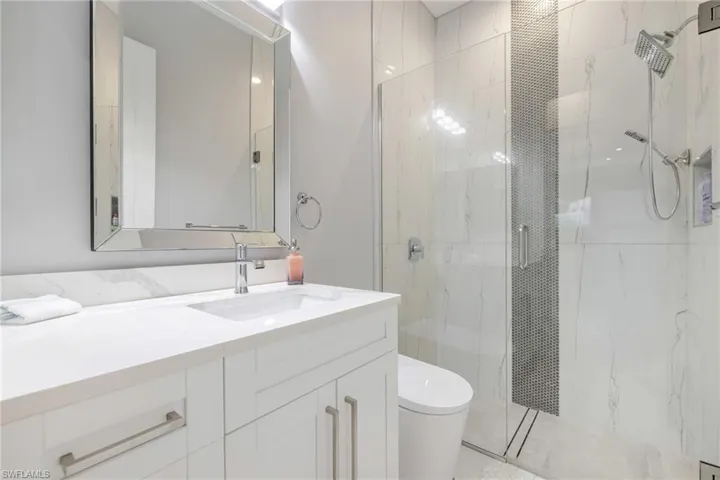 Bathroom with vanity and a marble finish shower