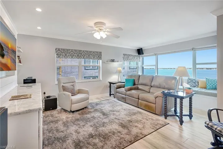 Living room with river view, crown molding, wood-like tile floor, impact windows.