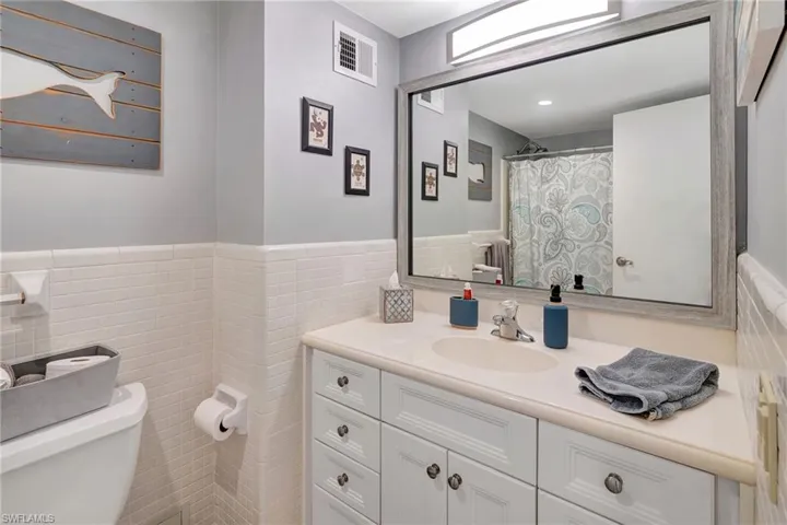 Full bathroom with vanity and tile walls