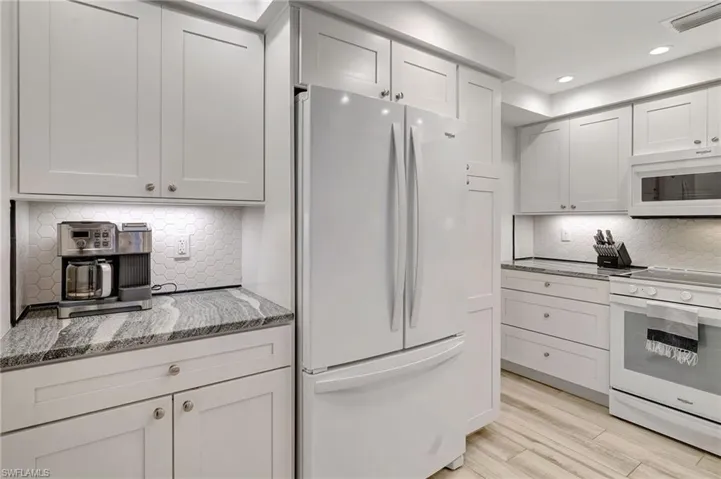 Kitchen featuring white appliances, tiled backsplash & recessed lighting