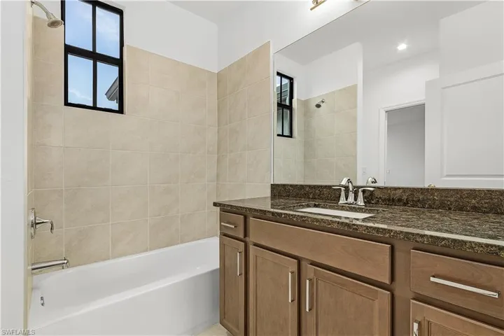 Bathroom with a healthy amount of sunlight, vanity, and tiled shower / bath