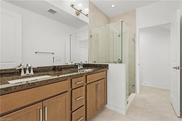 Bathroom with vanity, a shower with shower door, and tile patterned flooring