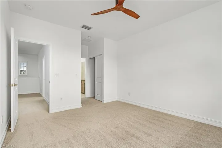 Unfurnished bedroom with light carpet and ceiling fan