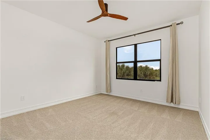 Carpeted spare room featuring ceiling fan