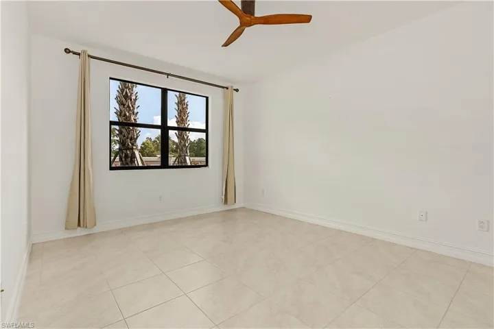 Unfurnished room with ceiling fan and light tile patterned floors