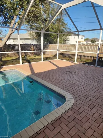 View of swimming pool featuring glass enclosure and a fenced backyard