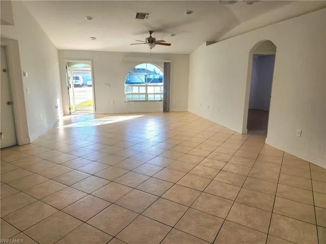 Empty room with arched walkways, a ceiling fan, light tile patterned floors, and recessed lighting