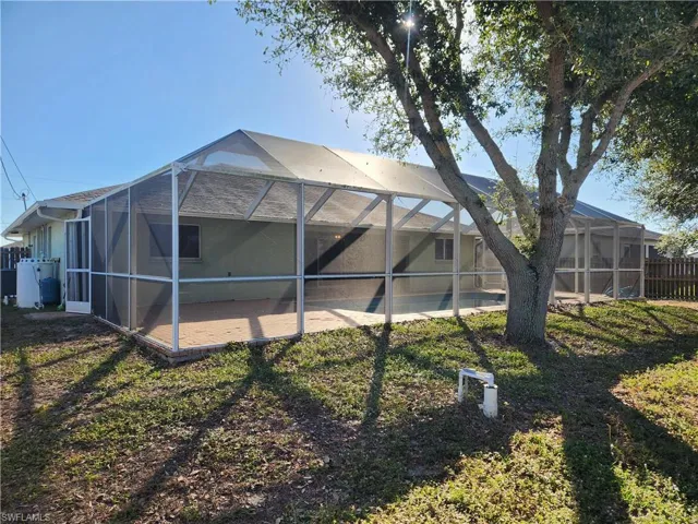 Rear view of property featuring a sunroom, glass enclosure, and a pool