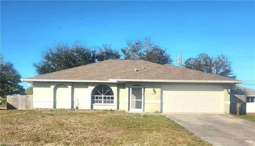 Ranch-style home with stucco siding, roof with shingles, driveway, and an attached garage