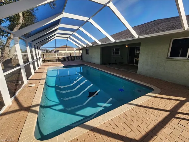Swimming pool with a sunroom, glass enclosure, and a patio area