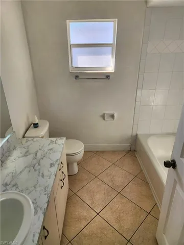 Full bath featuring vanity, a tub to relax in, and light tile patterned floors