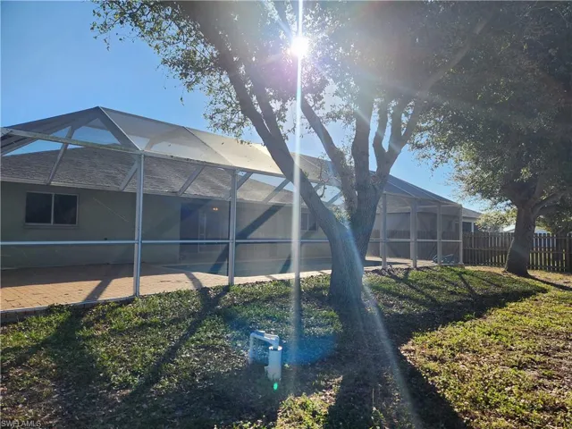 Rear view of property featuring a lanai, a sunroom, and a fenced backyard