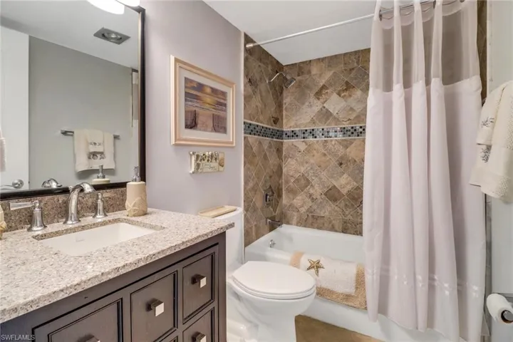 Full bathroom with toilet, vanity, and shower / tub combo with curtain