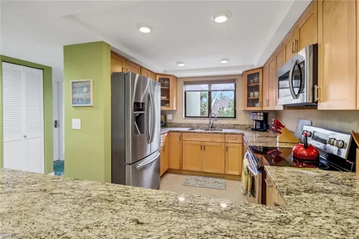 Kitchen with sink, light stone counters, kitchen peninsula, and stainless steel appliances