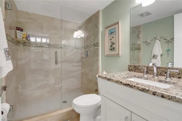 Bathroom featuring vanity, a shower with shower door, and toilet