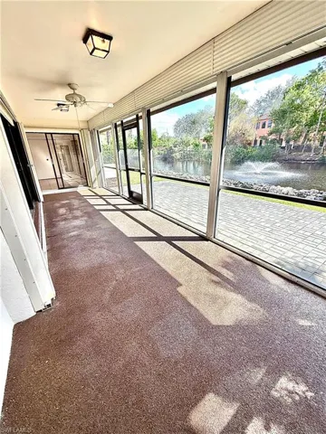 Unfurnished sunroom featuring ceiling fan and a water view