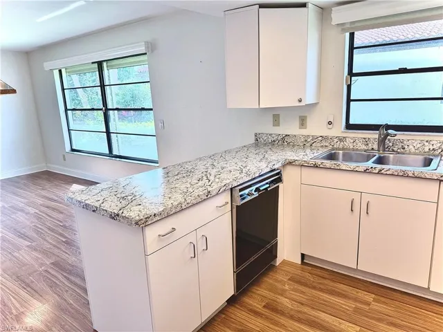 Kitchen with white cabinetry, dishwasher, sink, and light wood-type flooring