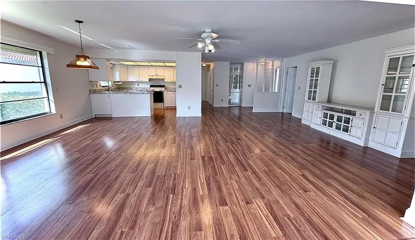 Unfurnished living room with ceiling fan and dark hardwood / wood-style flooring