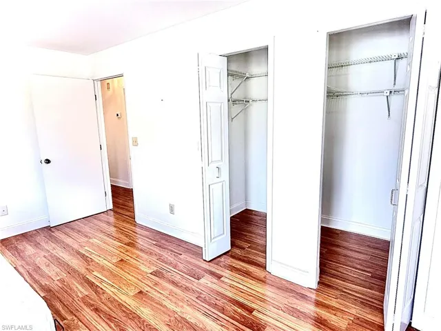 Unfurnished bedroom featuring multiple walk-in closets and light hardwood / wood-style flooring