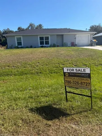 Single story home with a front yard, concrete driveway, and a garage