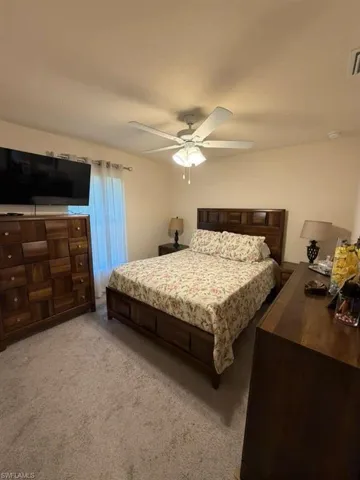 Bedroom with light colored carpet and a ceiling fan