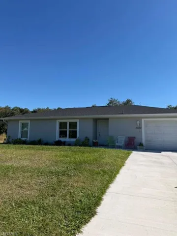 Ranch-style house with a front yard, concrete driveway, stucco siding, and an attached garage