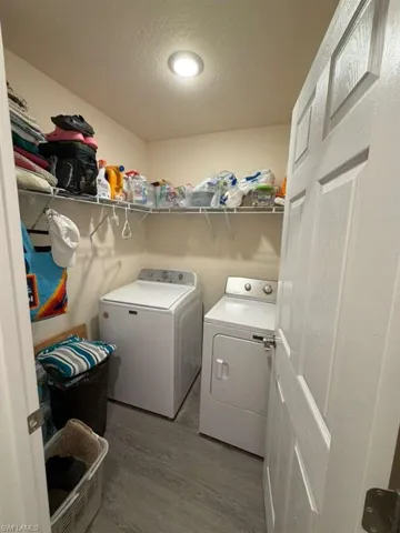 Laundry area with a textured ceiling, light wood finished floors, and washing machine and dryer