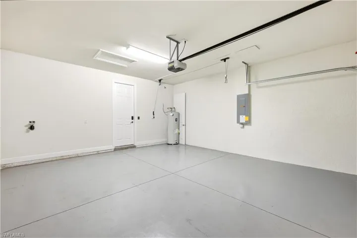 Spacious garage featuring a durable concrete floor, an overhead garage door opener, and a panel door for interior access