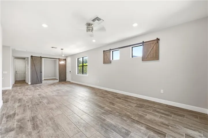 Spacious interior featuring wood-finish tile flooring, recessed lighting, and a ceiling fan