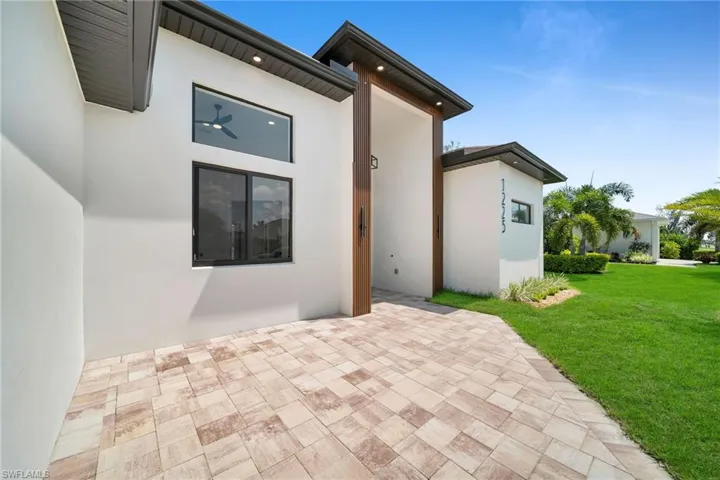 Doorway to property with a patio area and a lawn