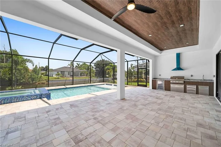 View of swimming pool with ceiling fan, area for grilling, a patio, and a lanai