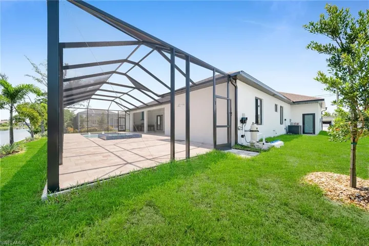 Back of property featuring a lawn, a lanai, central AC unit, and a patio area
