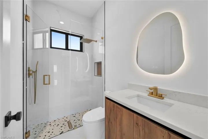 Bathroom with toilet, a shower with shower door, and vanity