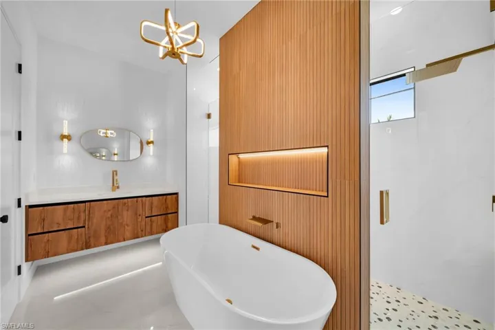 Bathroom with tile patterned floors, a notable chandelier, vanity, and shower with separate bathtub