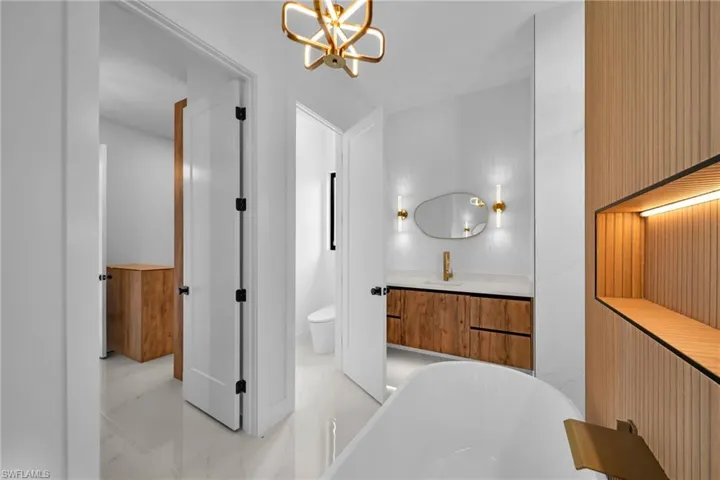 Bathroom featuring a chandelier, a bath, vanity, tile patterned flooring, and toilet