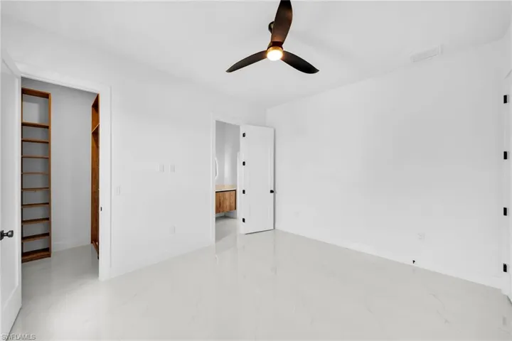 Unfurnished bedroom with ceiling fan, a closet, a spacious closet, and light tile patterned floors