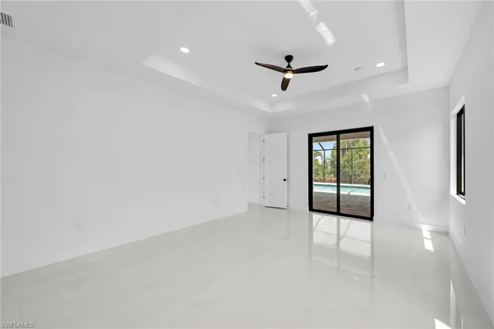 Tiled spare room with ceiling fan and a tray ceiling