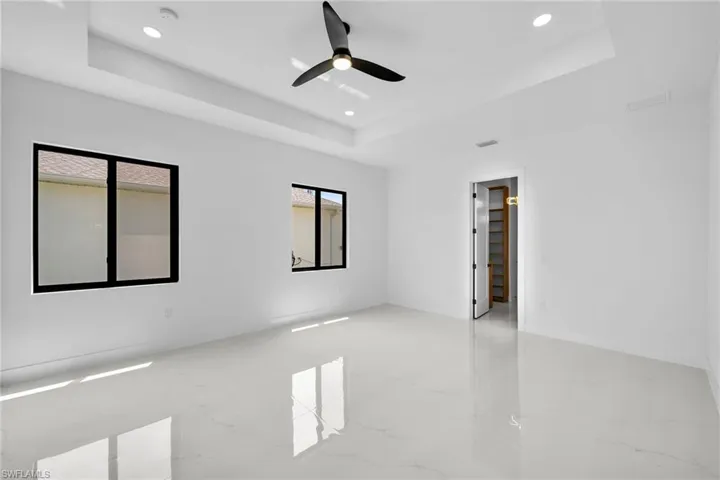 Tiled spare room featuring ceiling fan and a tray ceiling