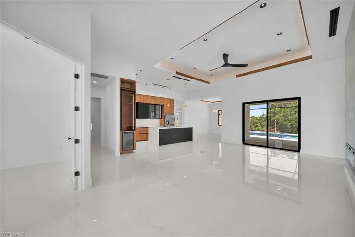 Unfurnished living room with light tile patterned floors, a raised ceiling, and ceiling fan