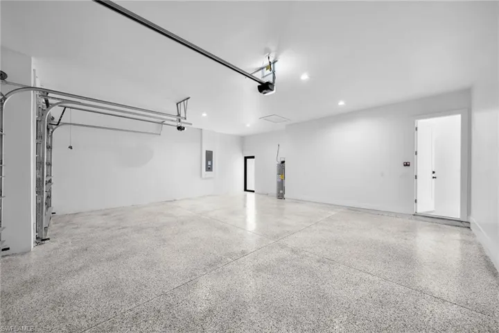 Garage featuring a garage door opener, water heater, and electric panel
