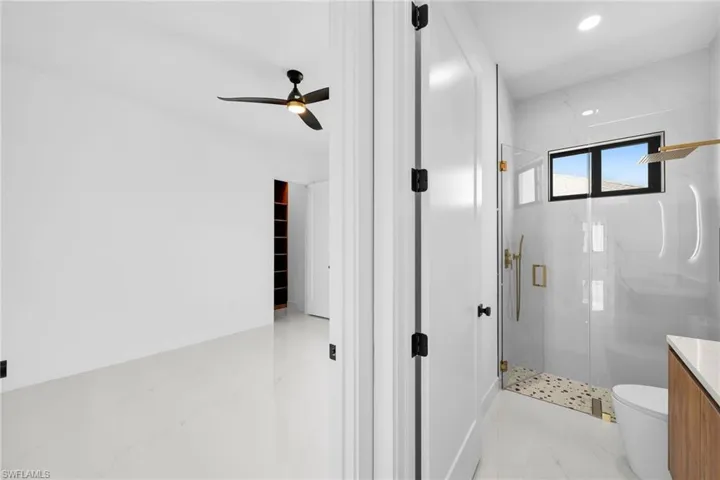 Bathroom featuring tile patterned flooring, toilet, an enclosed shower, and vanity
