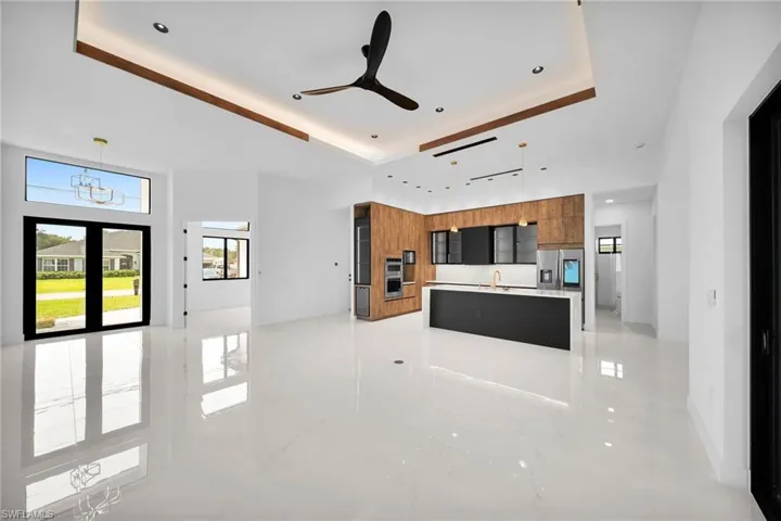 Kitchen featuring stainless steel appliances, sink, a raised ceiling, light tile patterned floors, and ceiling fan