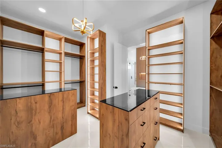 Walk in closet with a chandelier and light tile patterned floors