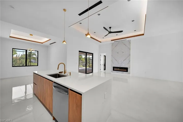 Kitchen with a fireplace, decorative light fixtures, a raised ceiling, and stainless steel dishwasher