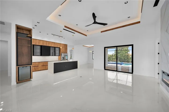 Kitchen with ceiling fan, a raised ceiling, stainless steel fridge with ice dispenser, and light tile patterned flooring