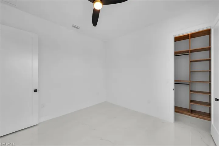 Unfurnished bedroom featuring tile patterned flooring, a closet, and ceiling fan
