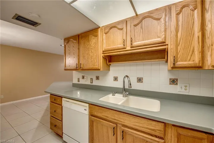 Kitchen featuring backsplash, dishwasher, light tile patterned flooring, and sink