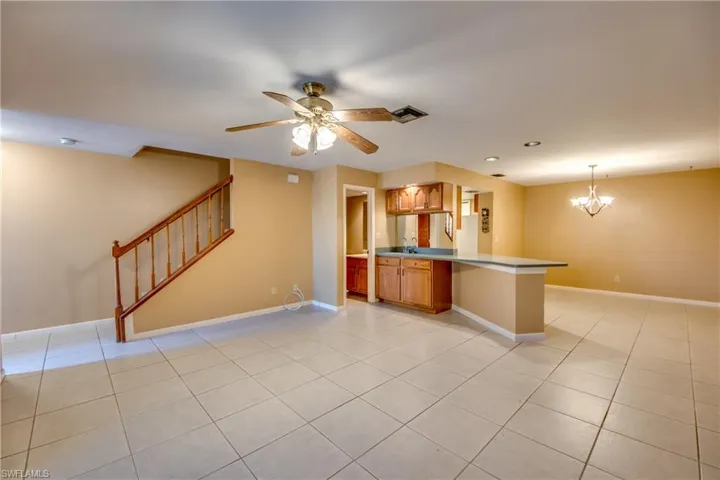 Kitchen with pendant lighting, light tile patterned flooring, sink, kitchen peninsula, and ceiling fan with notable chandelier