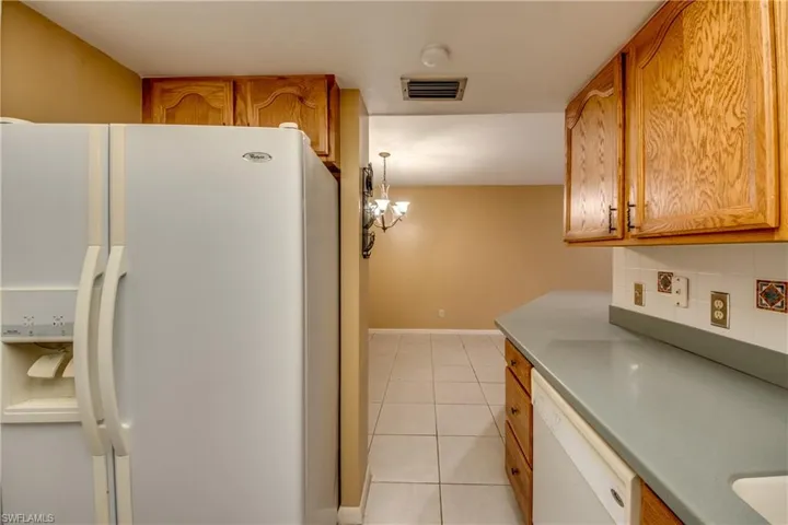 Kitchen featuring white appliances, light tile patterned flooring, a chandelier, and tasteful backsplash